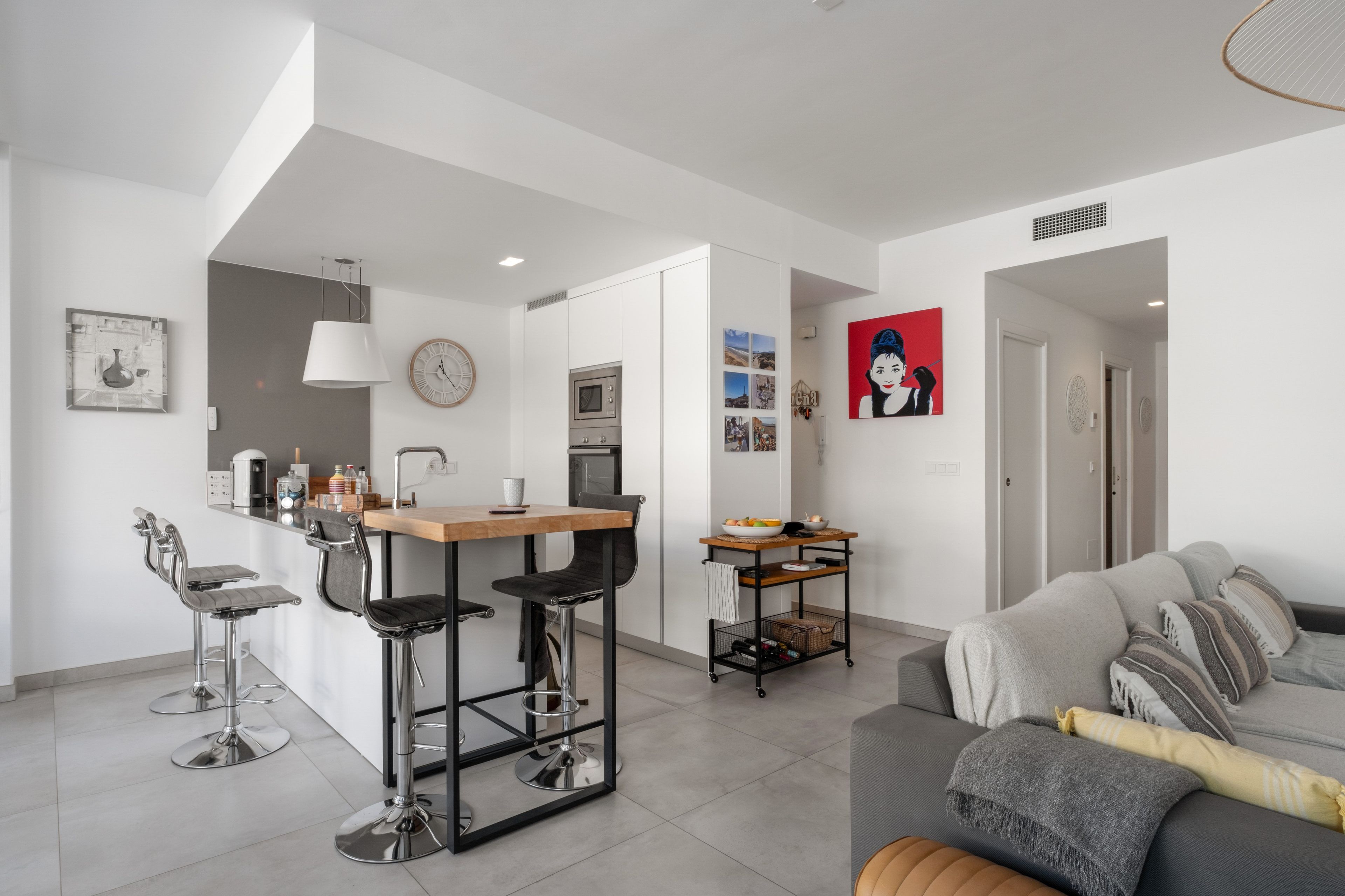 Um espaço de estar moderno com cozinha, sala de jantar e sofá.
