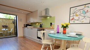 Een moderne keuken met witte kasten, een centraal eiland en een eethoek met een turquoise tafel en witte stoelen.