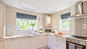 Una cucina moderna con pensili e basi bianchi, un forno a microonde, un bollitore ed una stufa.