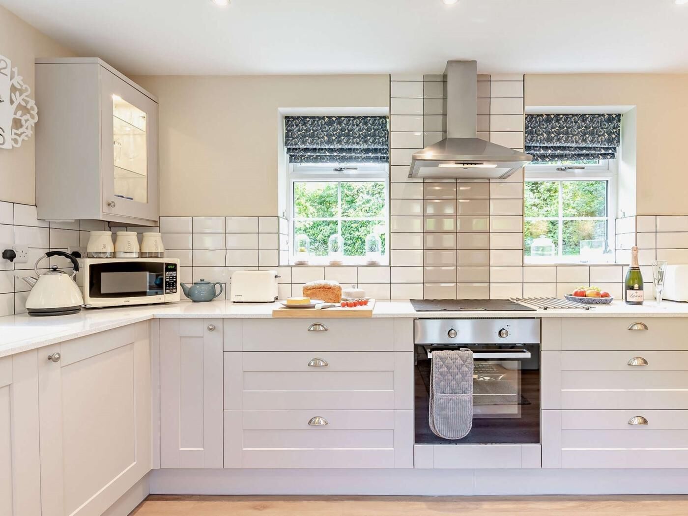 Une cuisine moderne avec des meubles blancs, un four encastré, un four à micro-ondes et une cuisinière à gaz.