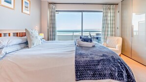 A hotel room with a bed, a chair, a large window with a view of the sea, and a wardrobe. - 3 Bed in Bideford (oc-41059) (Westward Ho!)