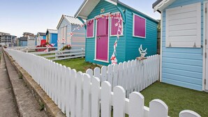 A row of colorful beach houses with white picket fences, each with a distinct color and a small garden area. - 3 Bed in Bideford (oc-41059) (Westward Ho!)