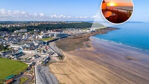 An aerial view of a coastal town with a beach, buildings, and a clear sky. - 3 Bed in Bideford (oc-41059) (Westward Ho!)