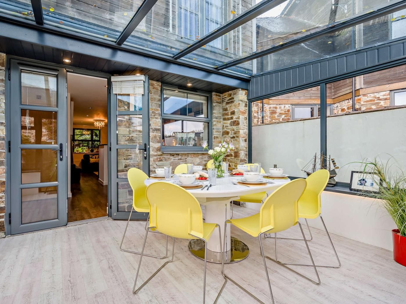 Een eetgedeelte met een glazen patio, stenen muren en gele stoelen.