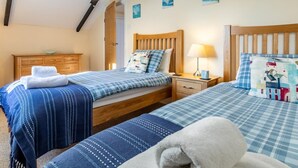 Ein Schlafzimmer mit zwei Betten, Holz-Kopfteilen, einem Nachttisch mit Lampe und einer Holzkommode.