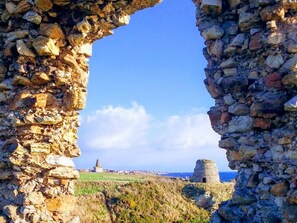 A stone archway leading to a coastal landscape with ruins and a distant tower. - 1 Bed in Anstruther (oc-41693) (Saint Monans)