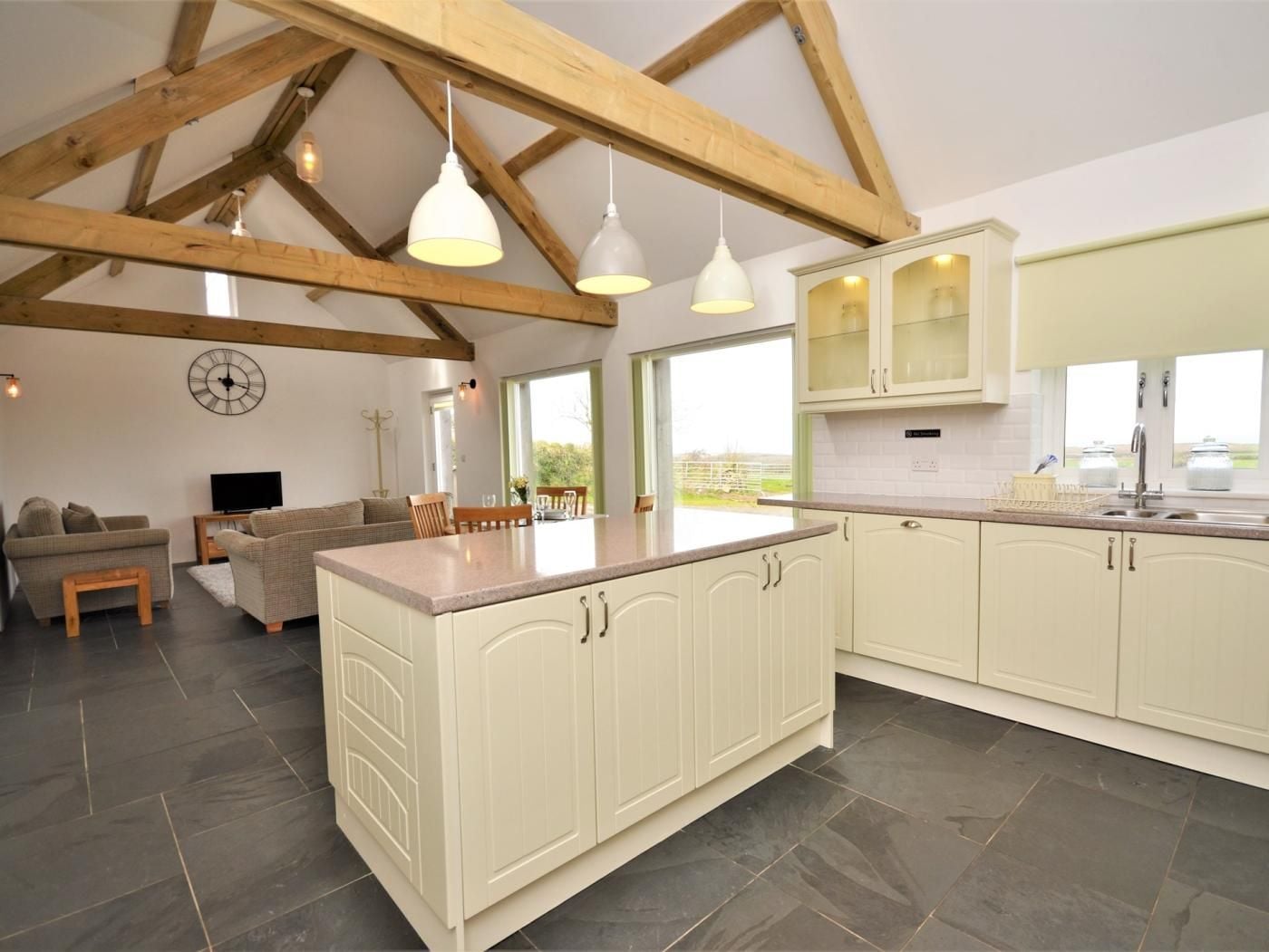 A spacious kitchen with a central island, white cabinetry, and a large window providing natural light.