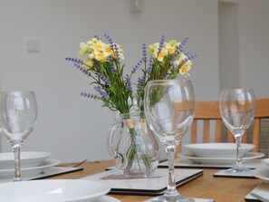 Ein Esstisch, gedeckt mit klarem Glas und einer Blumenvase.