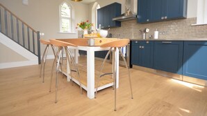 Una cocina moderna con una isla central, armarios azules y una escalera que sube a otro nivel.