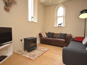 Una sala de estar con televisión, chimenea, sofá y lámpara.