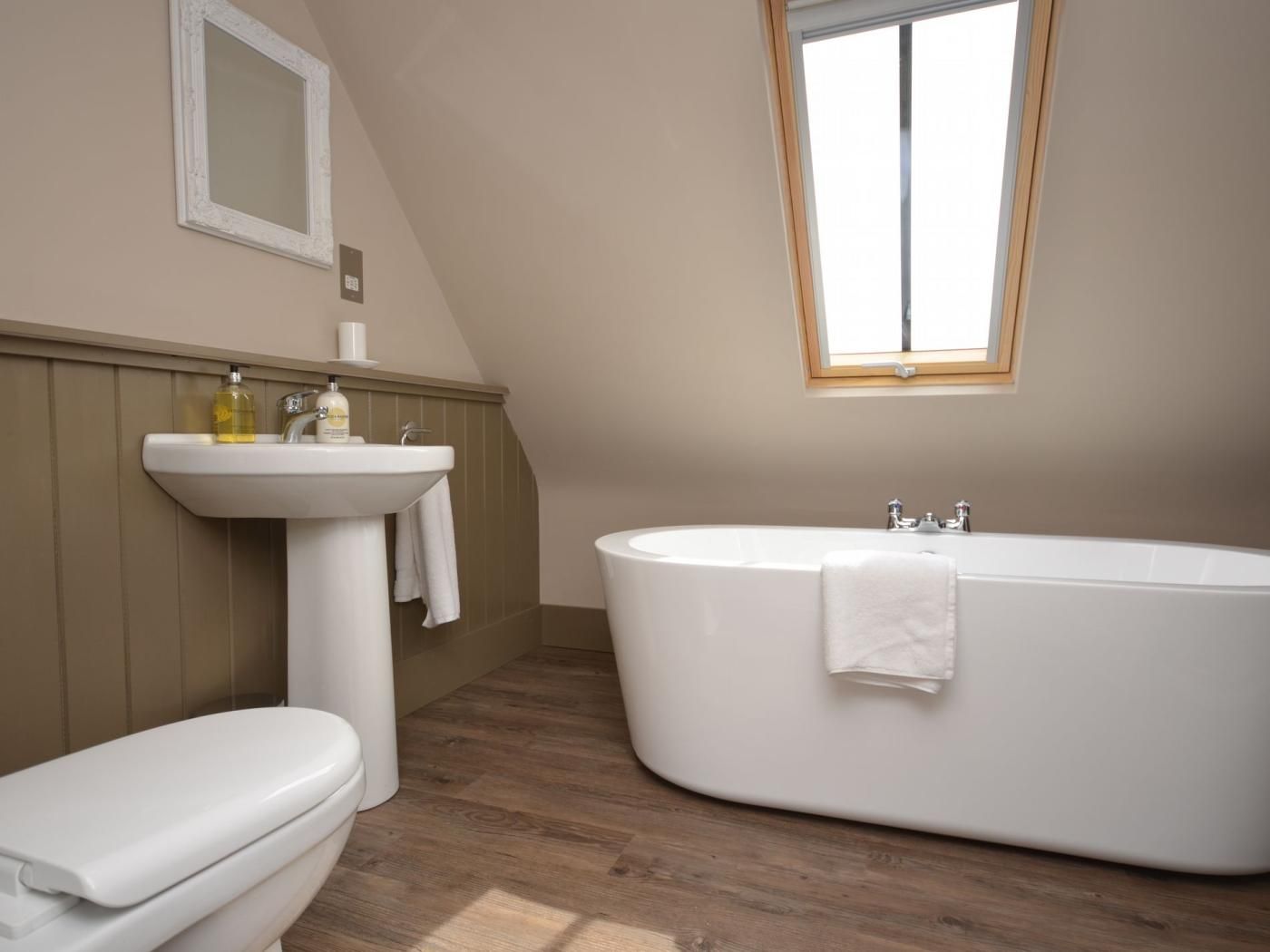 A bathroom with a freestanding bathtub, a pedestal sink, and a toilet.