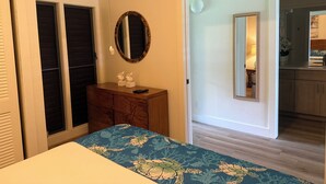 Ein Schlafzimmer mit einem Bett, einem Schminktisch, einem Spiegel und einer Tür zu einem Badezimmer.