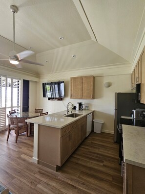 Una cocina moderna con una isla central, armarios de madera, horno empotrado y ventilador de techo.