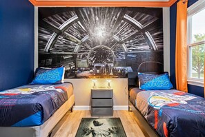 A bedroom with two beds, a Star Wars themed mural, and a desk with a lamp. - Galactic Oasis in Kissimmee (Davenport)