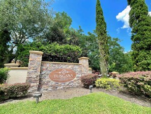 A stone wall with a sign for 'Tuscany Orlando Mediterranean Inspired Garden Condominiums.' - Galactic Oasis in Kissimmee (Davenport)