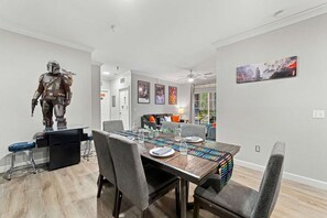 Een eetgedeelte met een tafel voor vier personen, een standbeeld van een personage en kunstwerken in lijsten aan de muur.