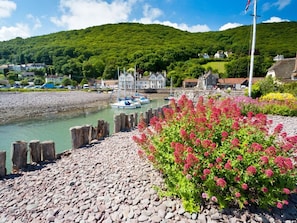 A coastal village with boats docked, a rocky shoreline, and houses with visible architecture. - 3 Bed in Minehead (oc-44078) (Porlock)