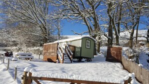 Un espacio exterior cubierto de nieve con una estructura de madera, un banco y una puerta.