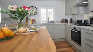 Una cocina moderna con encimera de madera, un lavamanos, una estufa y un reloj en la pared.