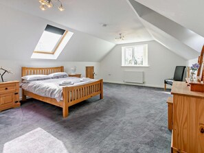 Une chambre avec un puits de lumière, un lit, une commode, une chaise et un radiateur.