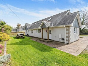 Une rangée de charmantes maisons blanches aux toits en pente, une pelouse verdoyante et une table de pique-nique.