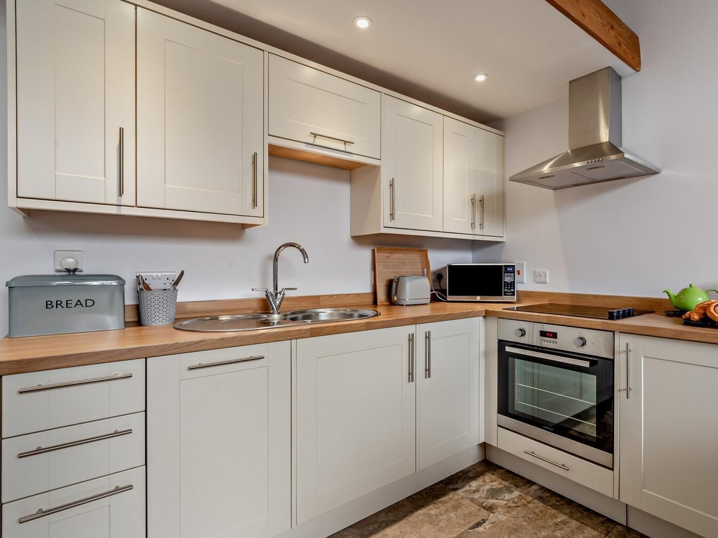 A modern kitchen with white cabinets, a stainless steel sink, a microwave, a toaster, and an oven.