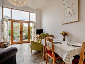 A dining area with a table set for two, a television, and a view of the garden through glass doors. - 1 Bed in Gillingham (oc-46774) (Bourton)