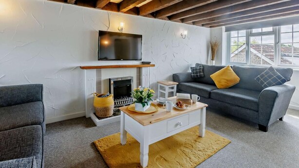 Un salon avec une cheminée, un canapé, une table basse et un téléviseur fixé au mur.
