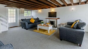 Un salon avec une cheminée, deux canapés, une table basse et un téléviseur fixé au mur.