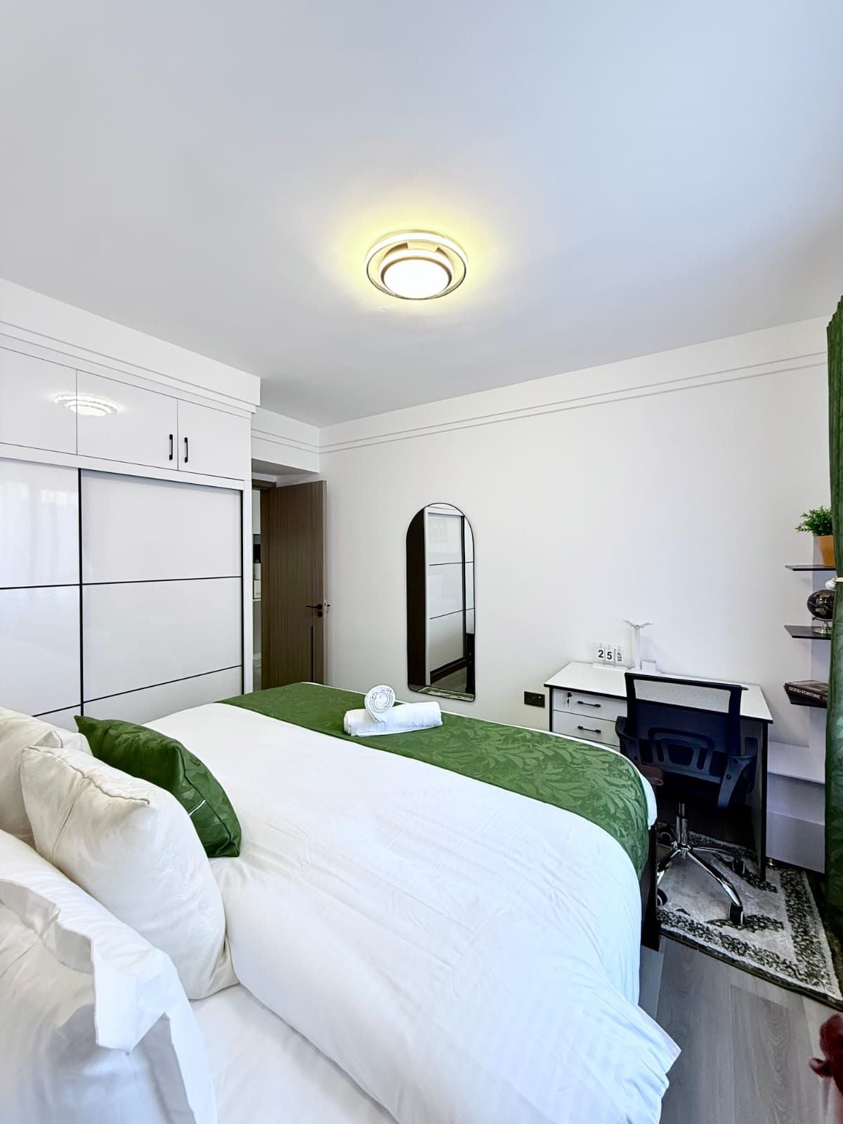 Una habitación de hotel con una cama, un escritorio, un espejo y un armario.