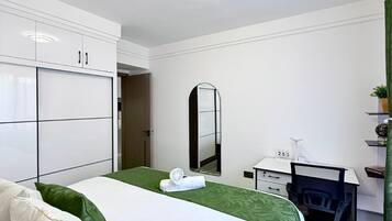 Una habitación de hotel con una cama, un escritorio, un espejo y un armario.