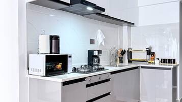 Una cocina moderna con microondas integrado, cafetera y estufa a gas.