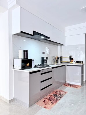 Una cocina moderna con microondas integrado, cafetera y estufa a gas.