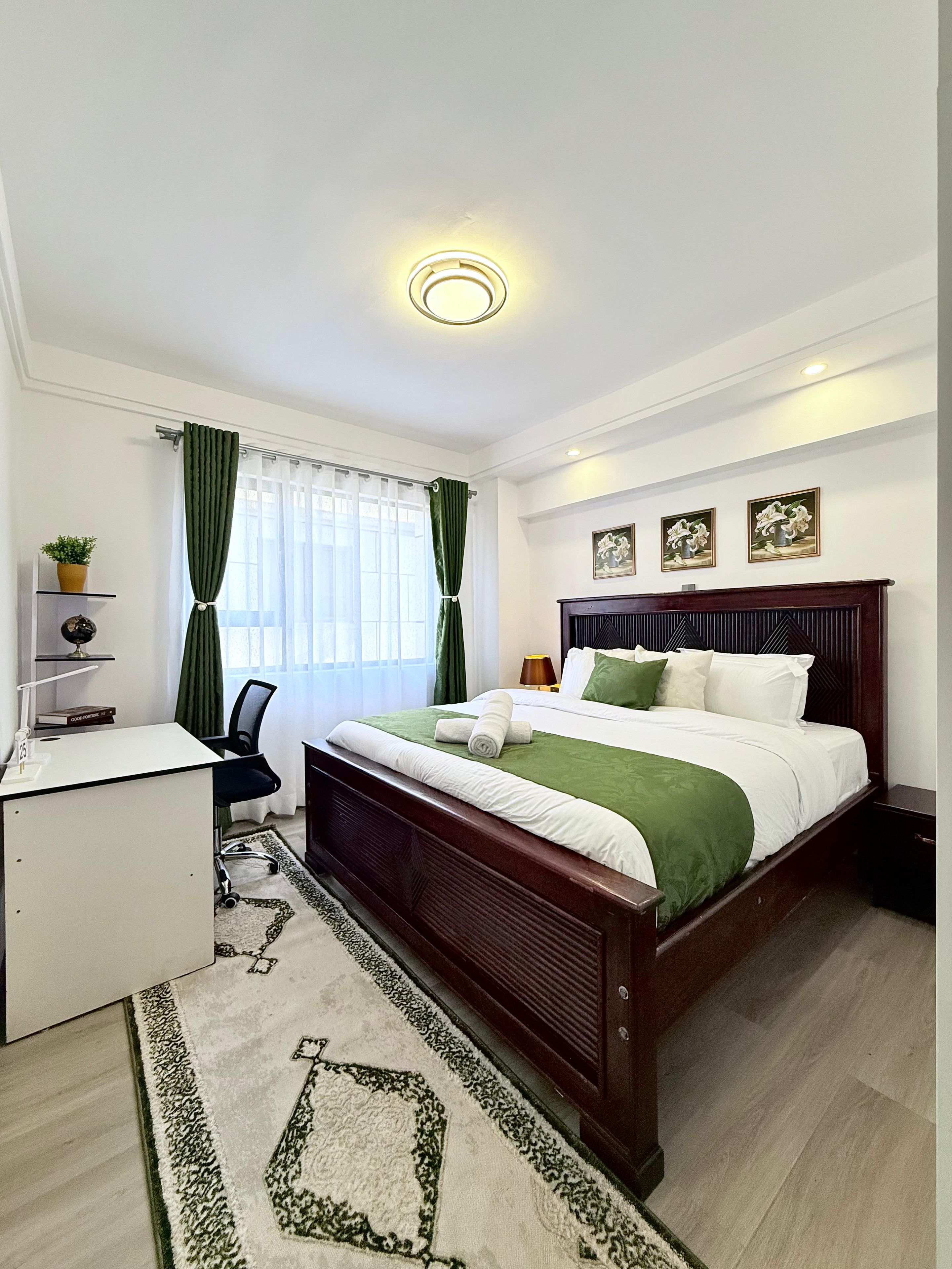 Habitación de hotel con cama, escritorio, silla y ventana con cortinas.