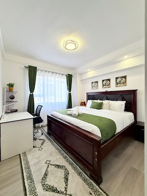 Habitación de hotel con cama, escritorio, silla y ventana con cortinas.