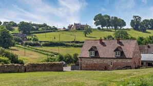 A rural landscape with a stone house featuring a tiled roof, surrounded by green fields and trees. - 2 Bed in Nottingham (oc-47032) (Newthorpe)