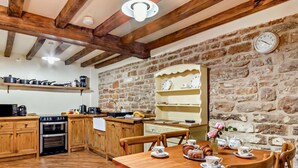 A rustic kitchen with wooden cabinets, a stone wall, and a dining table set for tea. - 2 Bed in Nottingham (oc-47032) (Newthorpe)