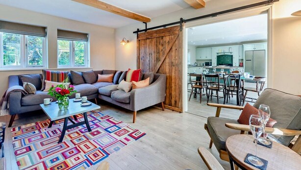 A modern living room with a sofa, coffee table, and a view into the kitchen. - 4 Bed in Matlock (oc-47450) (Brassington)