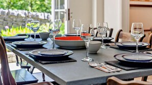 A dining table set with plates, glasses, and cutlery, with a view of greenery outside. - 4 Bed in Matlock (oc-47450) (Brassington)