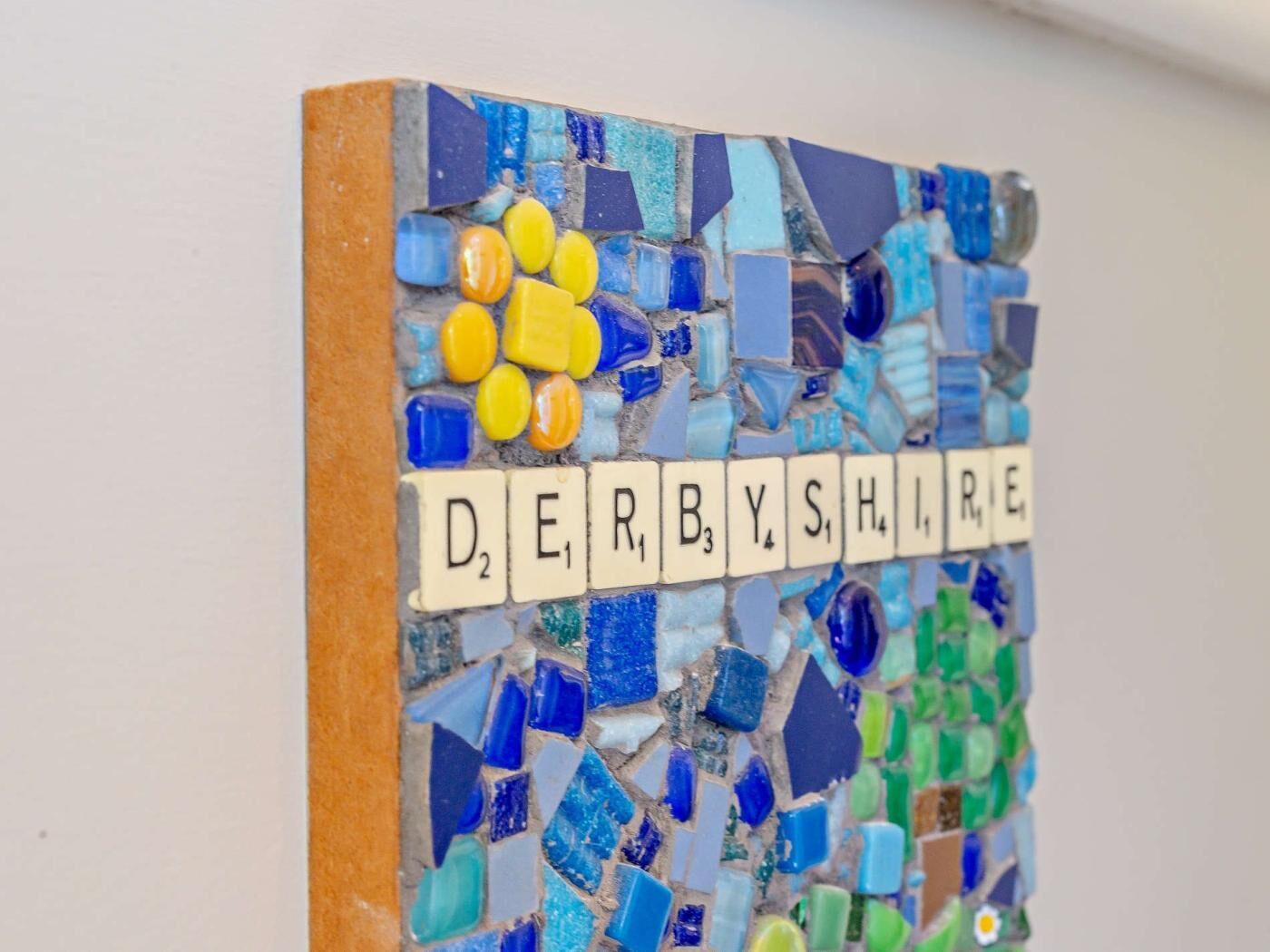 Un muro in mosaico con la scritta 'DERBYSHIRE' realizzata con piastrelle.