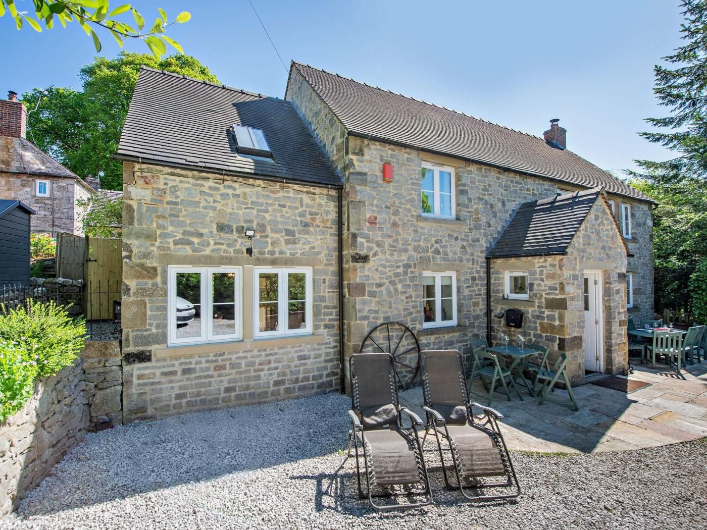 A stone house with a gravel driveway and outdoor seating area.