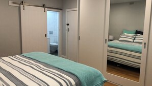 A bedroom with a bed, a mirror, and a sliding door leading to a bathroom.