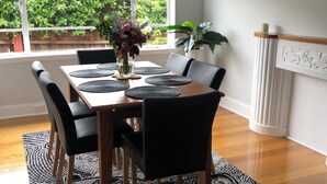 A dining area with a table set for four, surrounded by chairs, a patterned rug, and a window with a view of greenery.