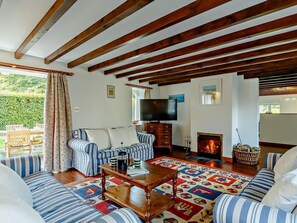 A living room with striped sofas, a coffee table, a fireplace, and a television. - 3 Bed in Liskeard (oc-47663) (Liskeard)
