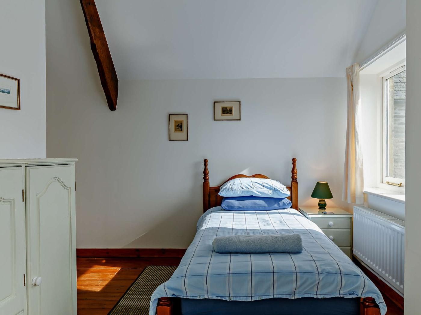 Quarto com cama, mesa de cabeceira, luminária, janela e guarda-roupa.