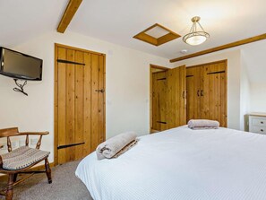 Ein Schlafzimmer mit einem Bett, einem Holzschrank, einem Sessel, einem Fernseher und einer Deckenleuchte.