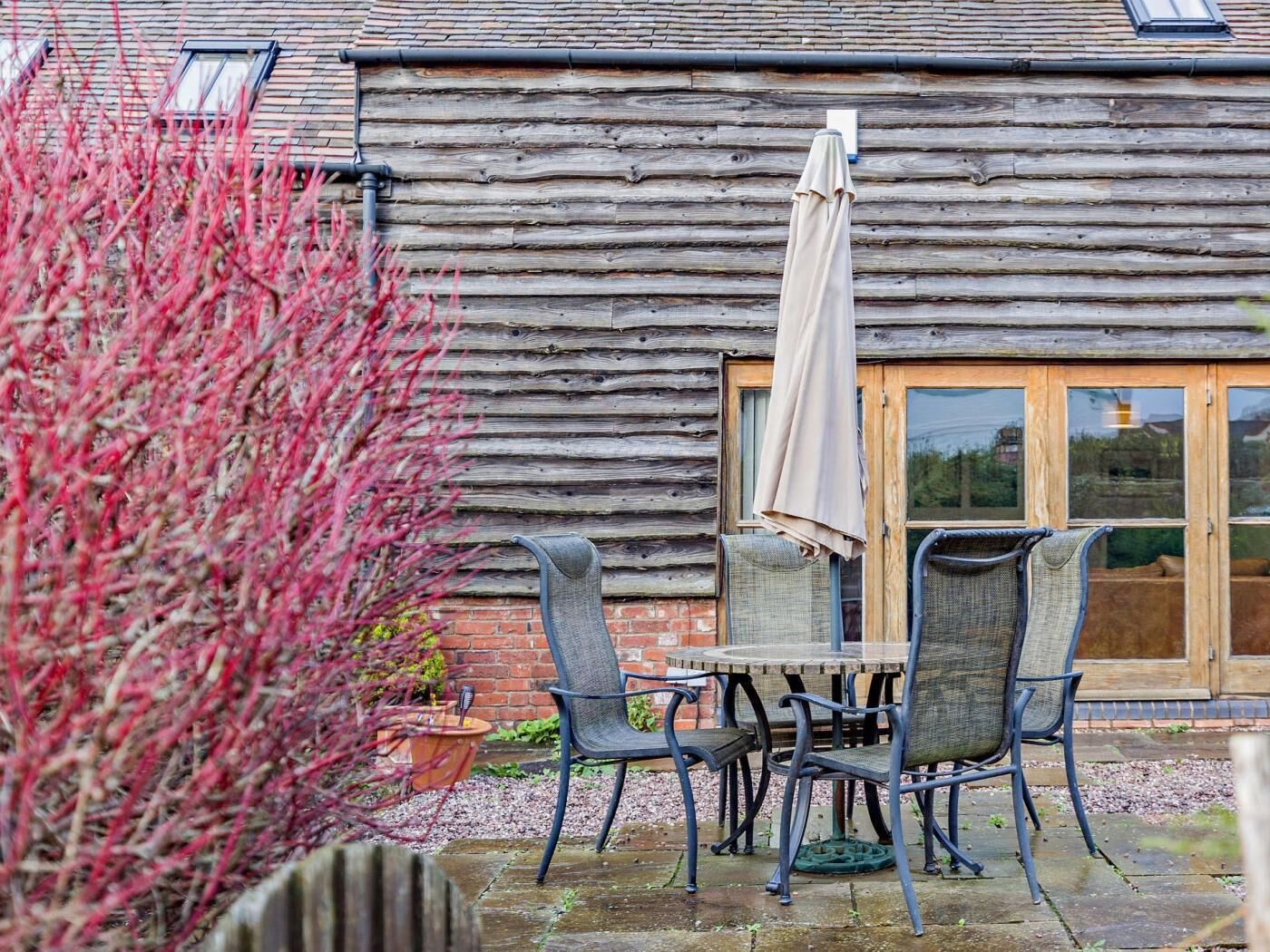 A rustic wooden building with a patio area featuring a table and chairs, a window, and a door.