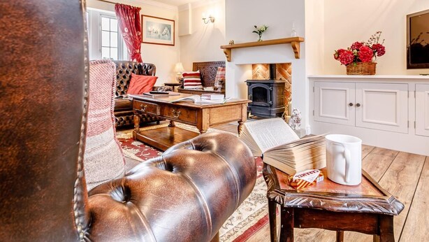A cozy living room with a fireplace, leather armchair, and a table with a book and mug. - 1 Bed in Sheffield (oc-48259) (Thurlstone)