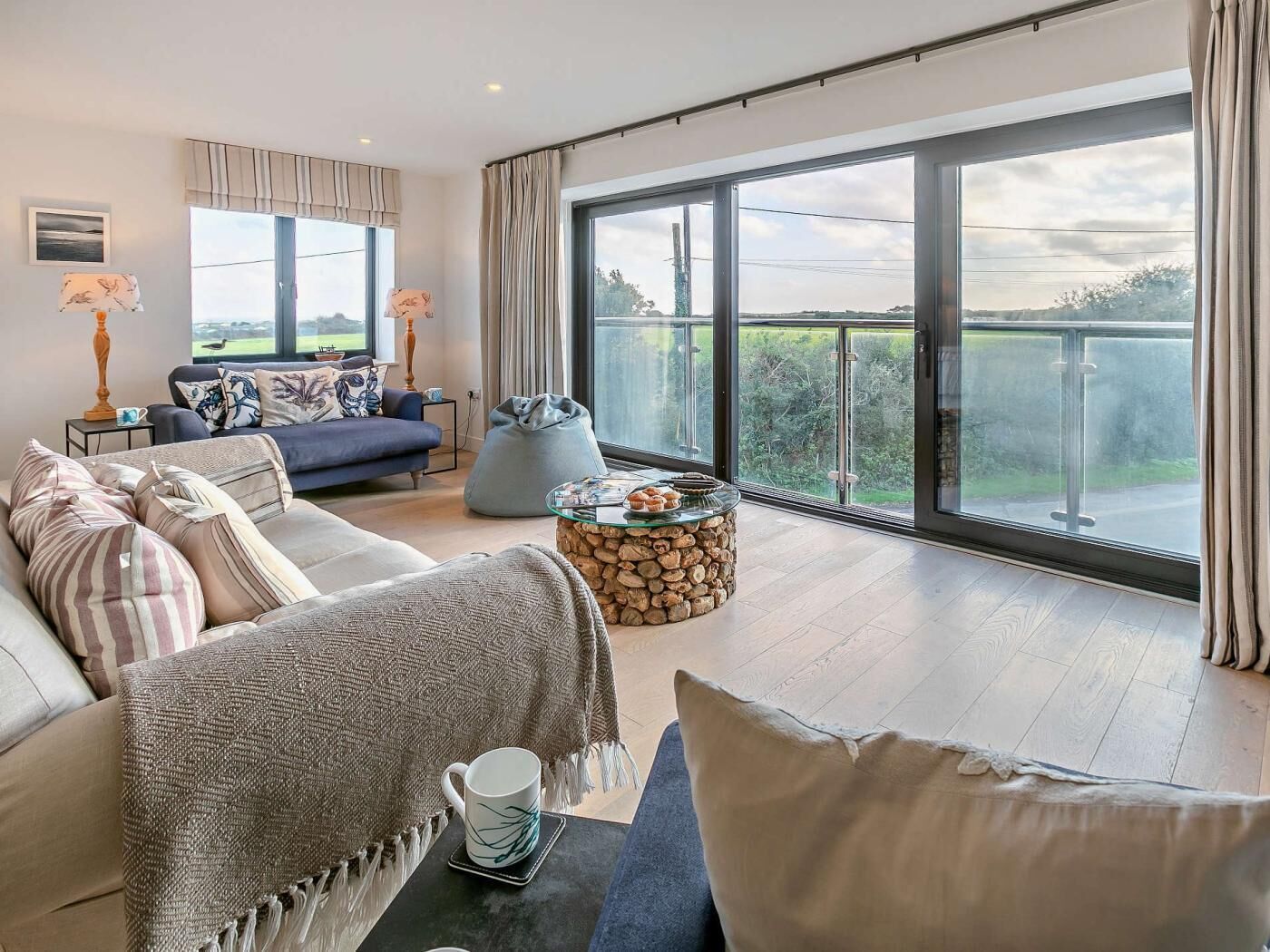 A modern living room with a sofa, a coffee table, and a view of the outdoors.