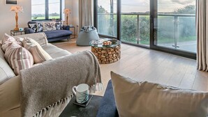 Ein modernes Wohnzimmer mit einer Couch, einem Couchtisch und Blick ins Freie.